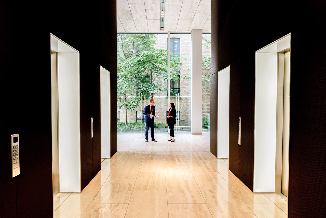 Two people having a discussion by the lobby lifts